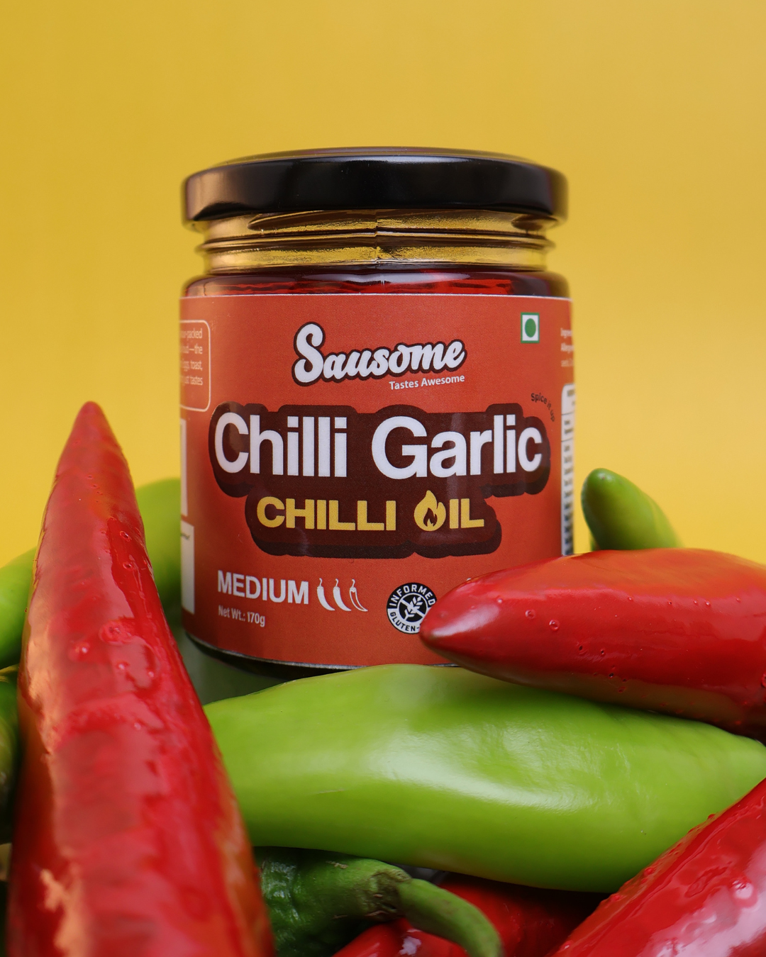 Jar of Sausome Chilli Garlic Chilli Oil surrounded by red and green peppers on a yellow background