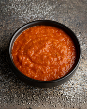 Black bowl filled with Chilli Garlic Chutney on a textured gray surface