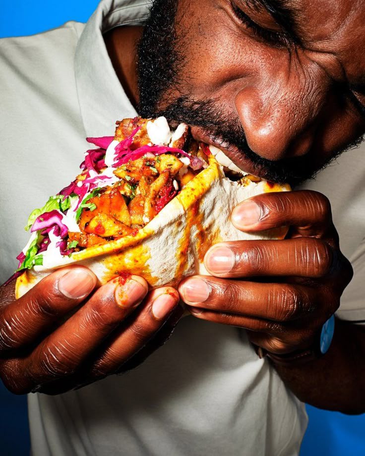 Person holding a large taco with colorful toppings 