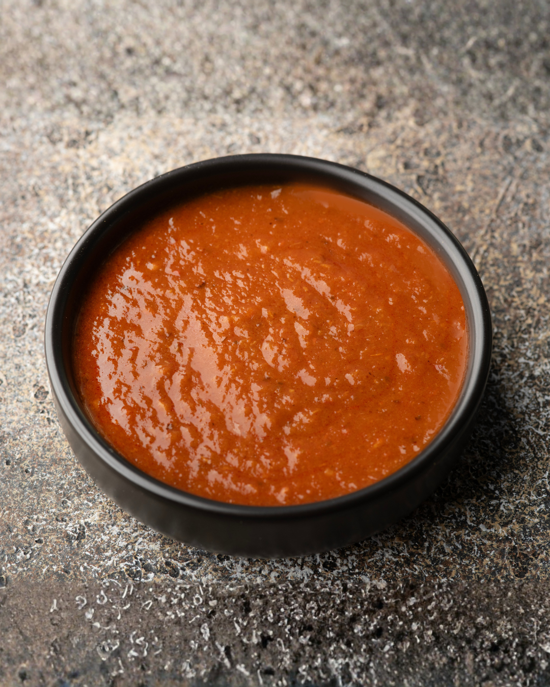 Black bowl filled with Sausome Momo Chutney on a textured gray surface