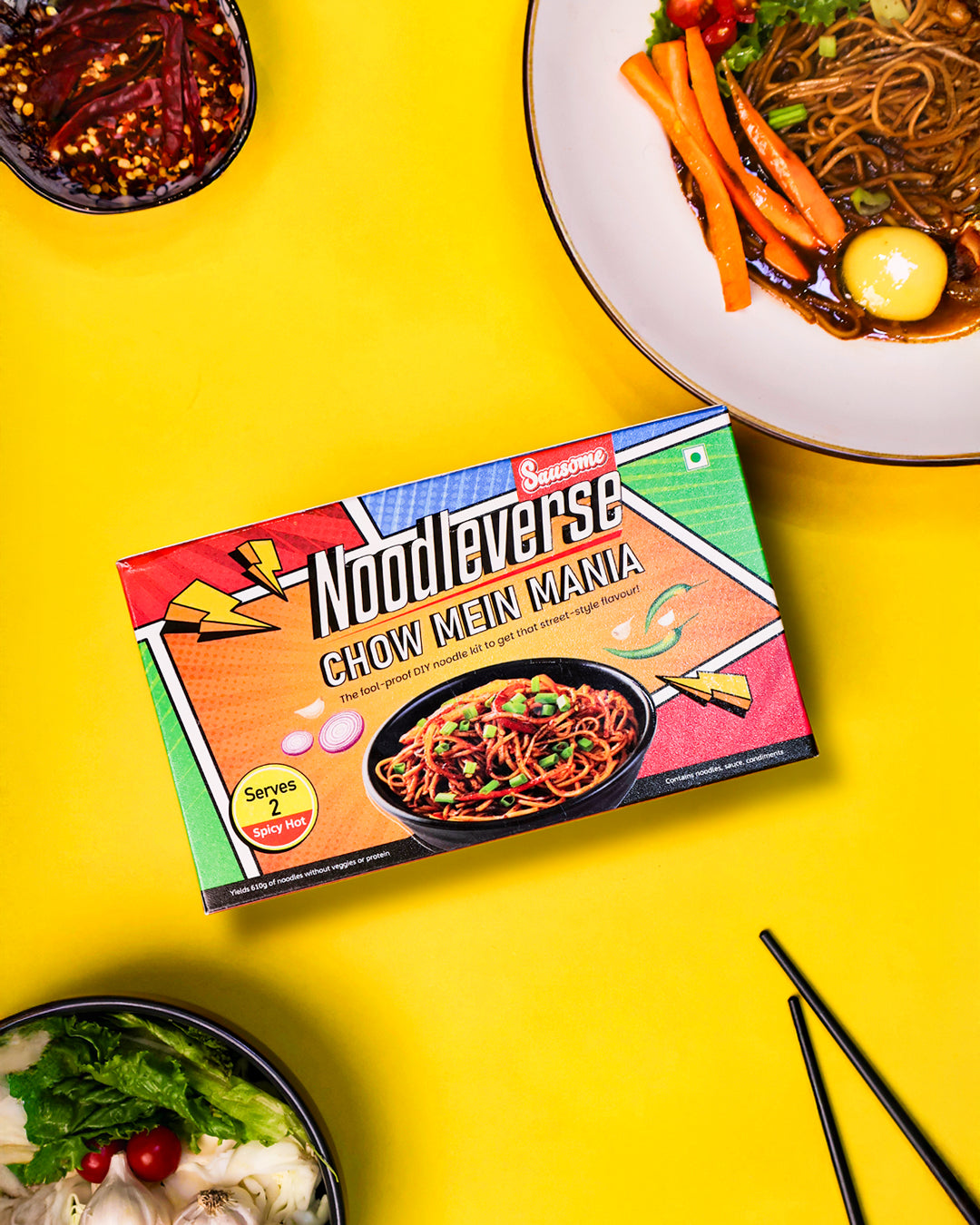 Chow Mein Mania noodle pack styled with fresh vegetables and chopsticks