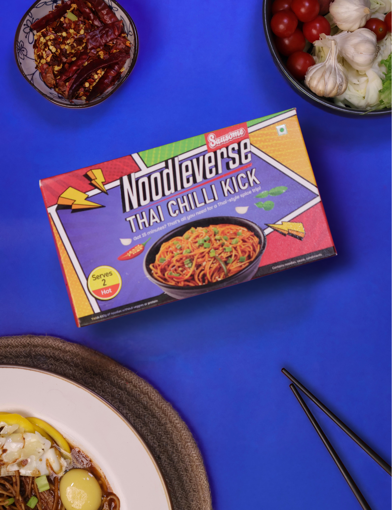 Noodlevsers Thai Chilli Kick noodle box on a blue background with food items around