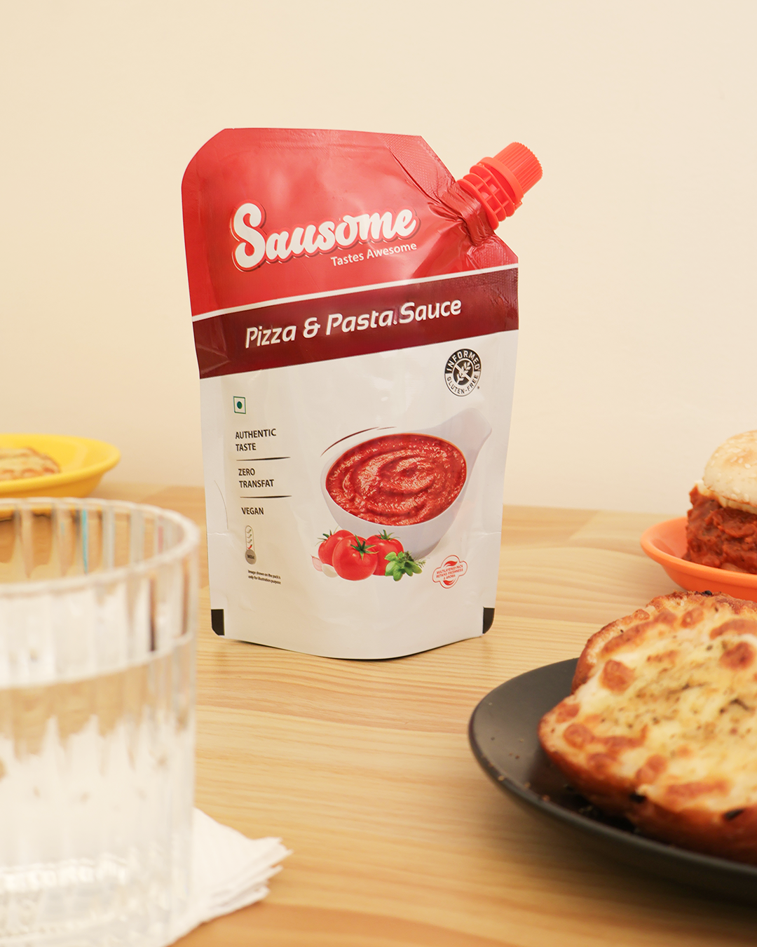 Sausome pizza and pasta sauce pack on a table with a pizza in the background