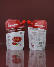 Two Sausome pizza and pasta sauce packages on a reflective surface with a red background.