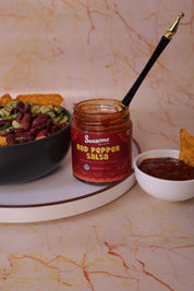 Sazon Red Pepper Salsa jar with a spoon on a marble surface