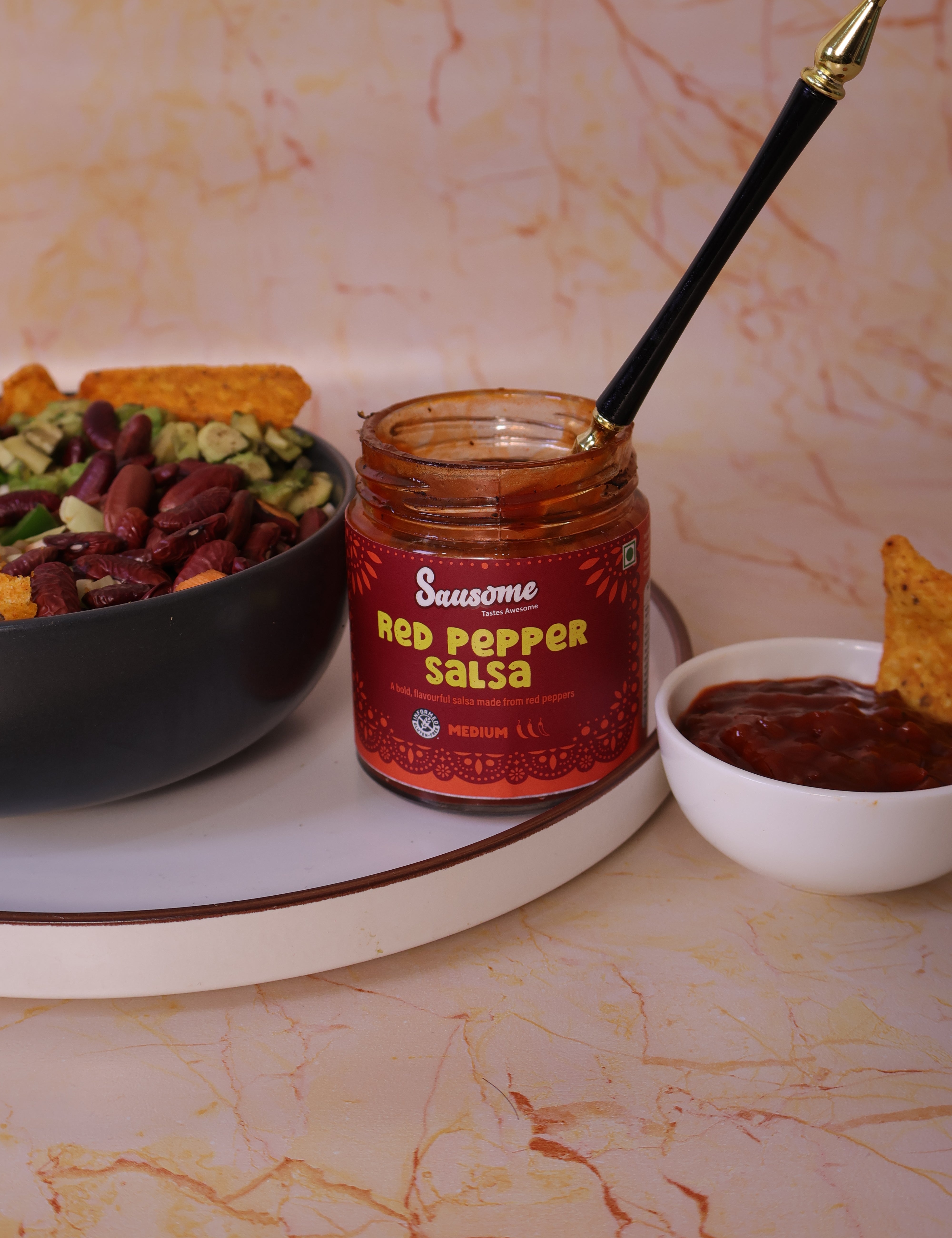 Sazon Red Pepper Salsa jar with a spoon on a marble surface