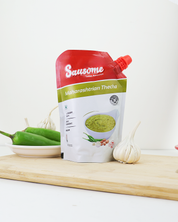 Sausome Maharashtrian Thecha packaging on a wooden board with ingredients in the background