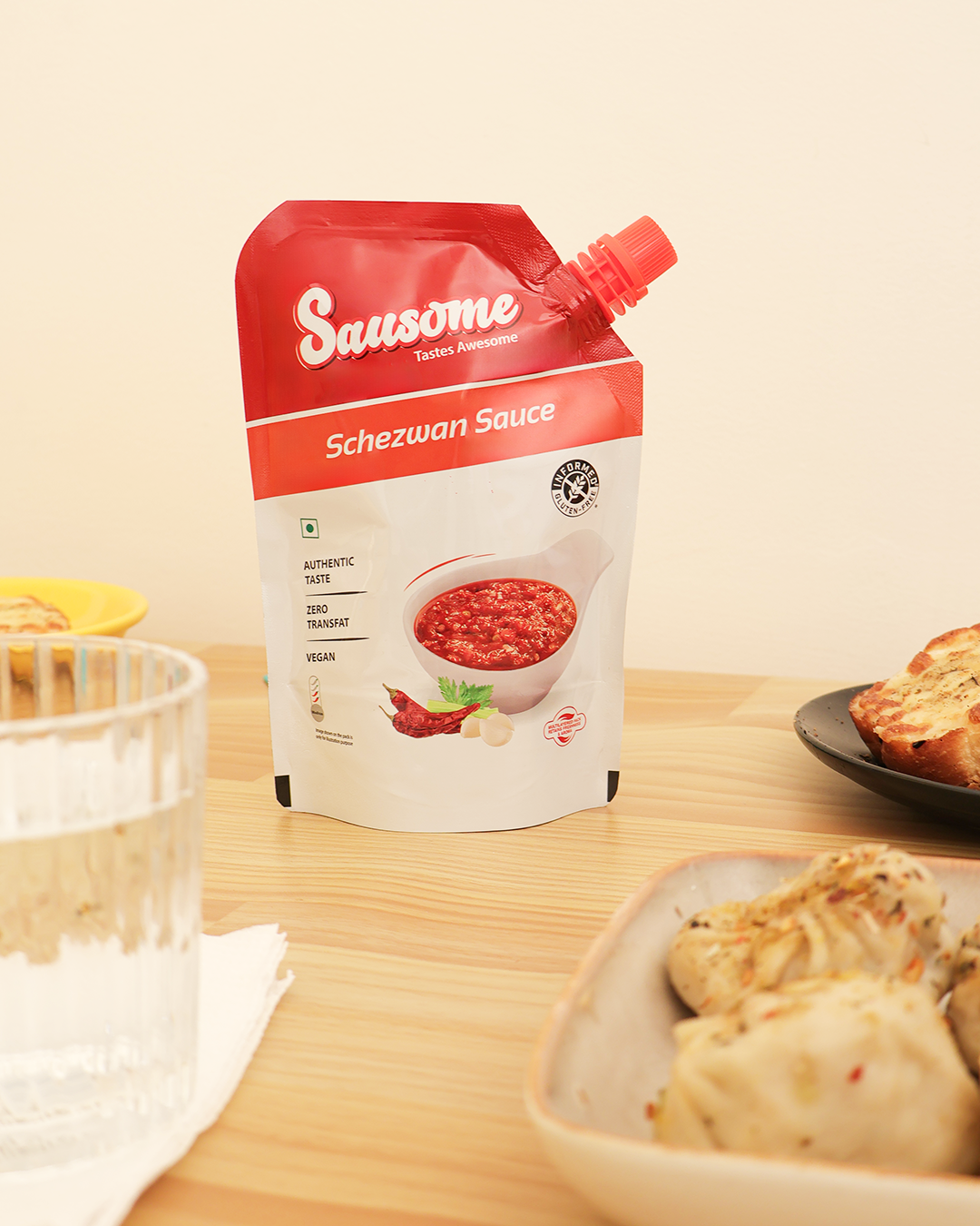 Sausome Schezwan Sauce packaging on a table with food items