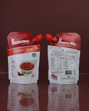 Two packages of Sausome Schezwan Sauce(Front & Back) on a reflective surface with a dark background