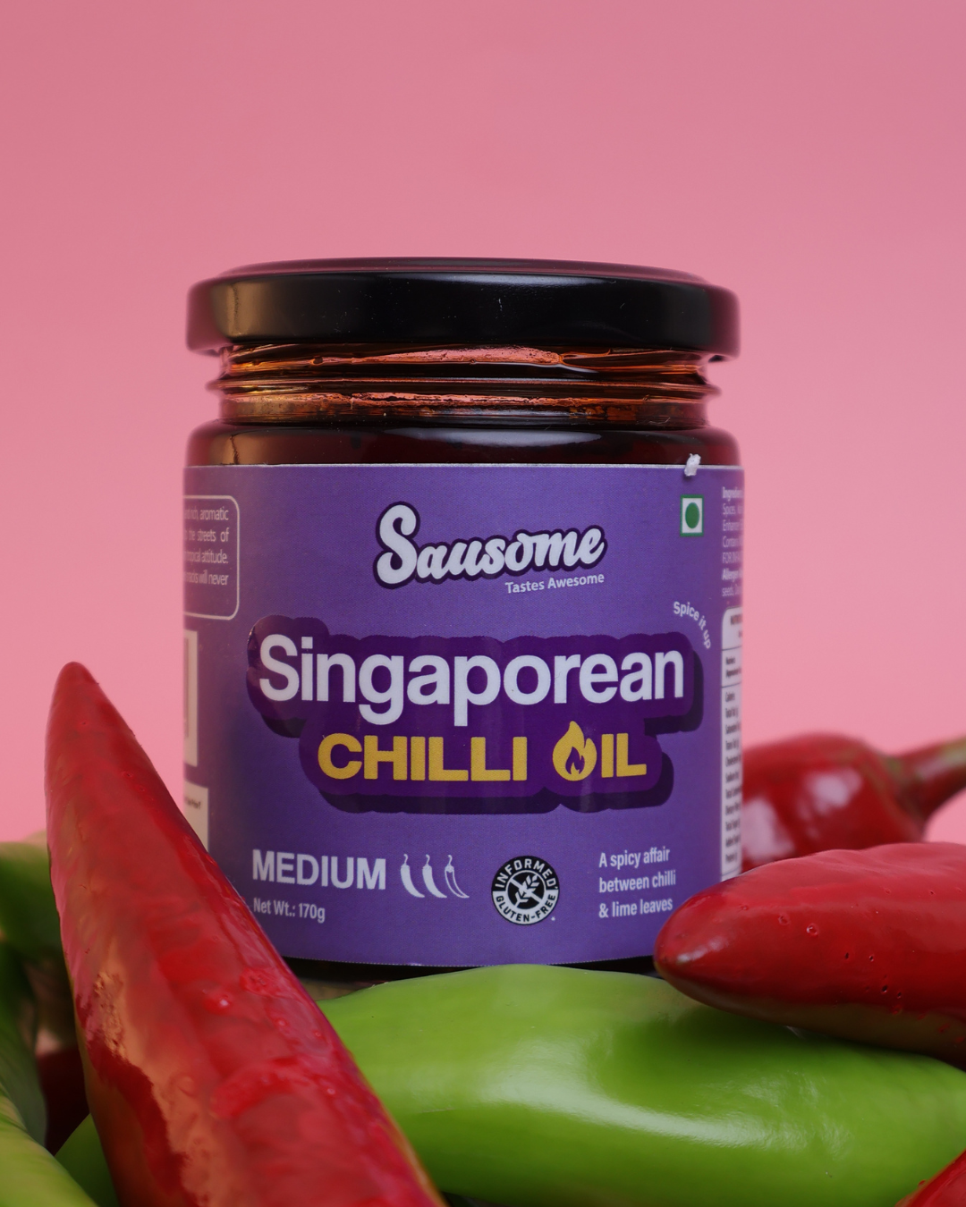 Jar of Sausome Singaporean Chilli Oil with chili peppers on a pink background